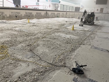 An empty olympic sizer pool, with machinary to grind out plaster and tile. 