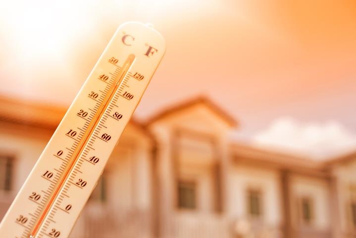 Image of a Temperature gauge reading 50 degrees celsius and 120 degrees fahrenheit. In the background of the photo is a domestic home.