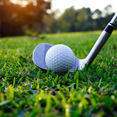 Green Grass with a white golf ball and golf club ready to be swung