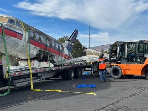 Plane fuselage arrives on a flatbed truck at Los Alamos Airport