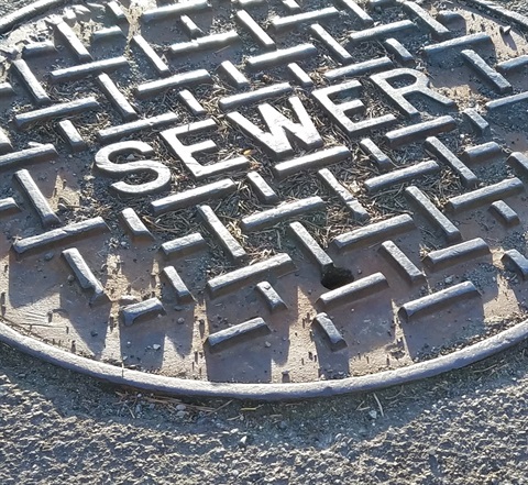 A sewer manhole cover on an asphalt surface
