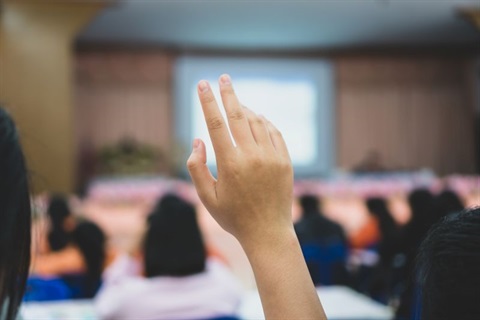 A hand is raised in a public meeting