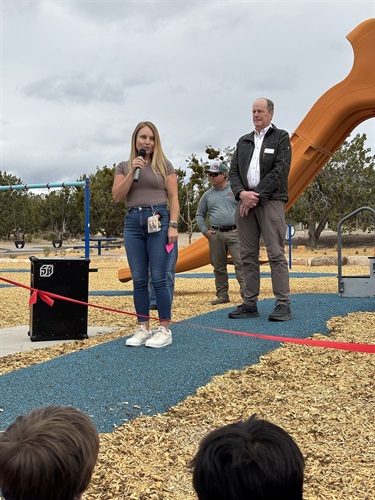 A woman speaks to a group of kids outdoors.