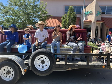 A group of people ride on a trailer in the County Fair parade.