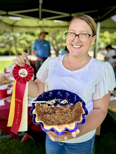 A woman displays her pie and her Reserve Champion ribbon at the Homemade Pie Contest.