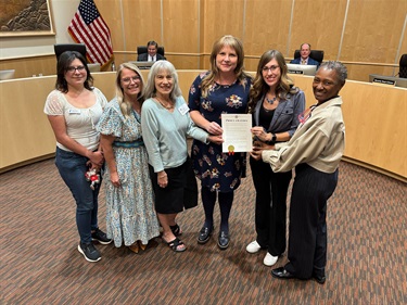 Six women stand together with a proclamation