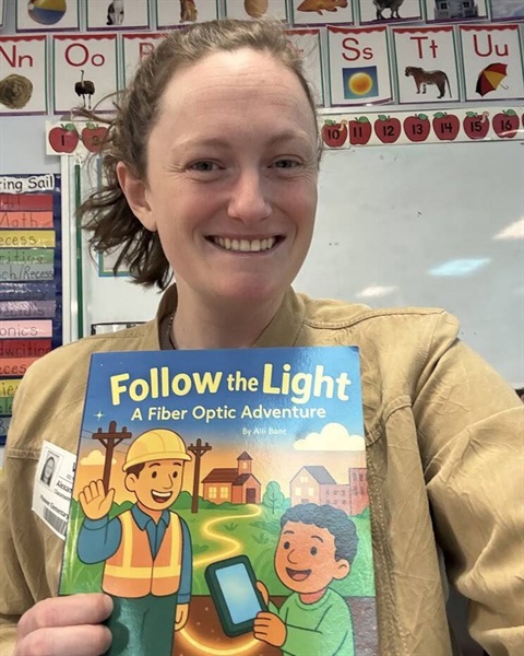A woman smiles while holding on a book with the title 