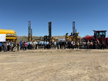 large group of people standing in front of construction equipment