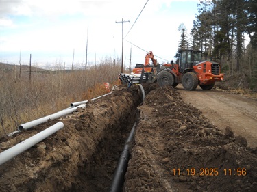 front loader installing conduit into trench