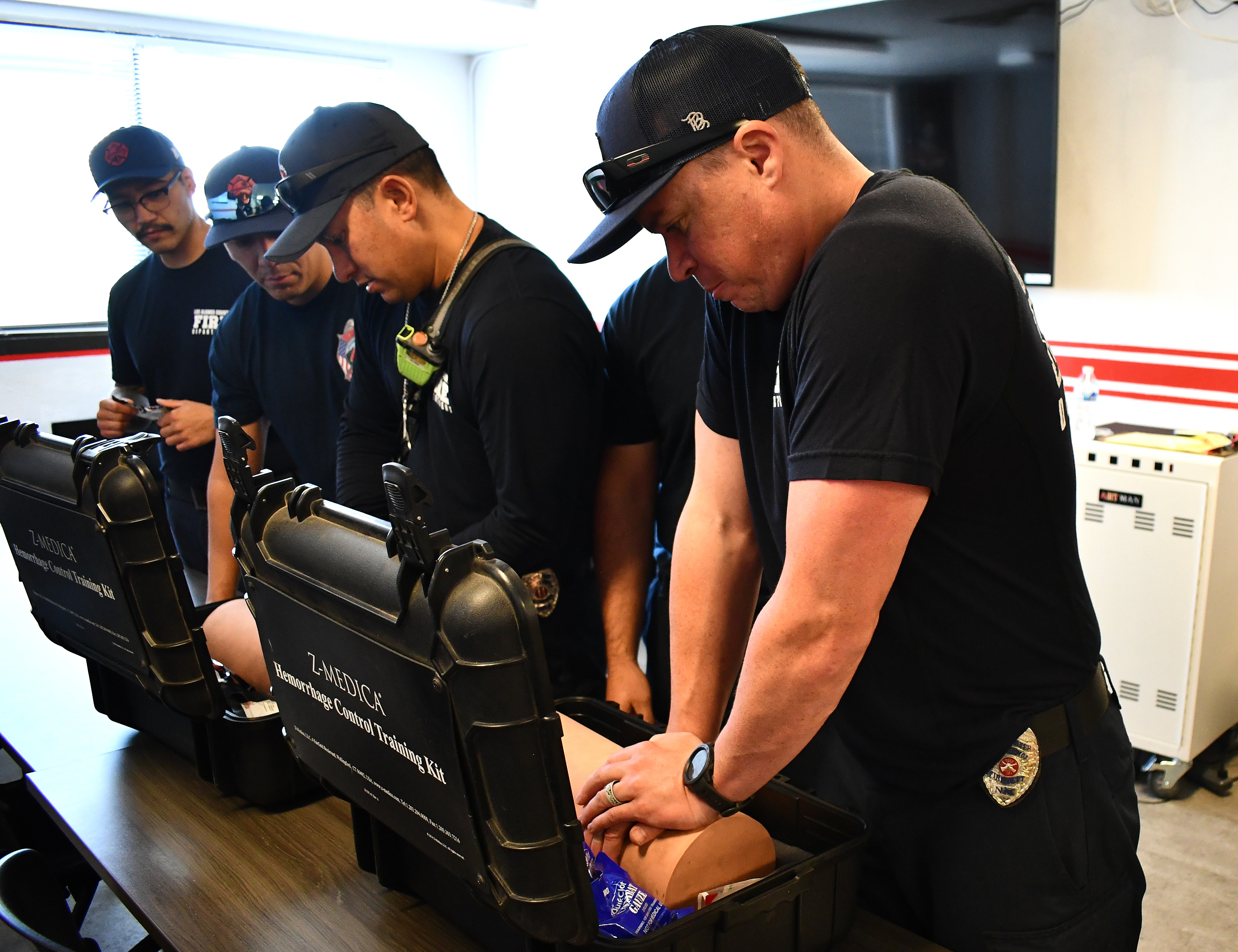 Four firefighters practice trauma wound packing