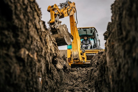 Stock photo of backhoe digging trench