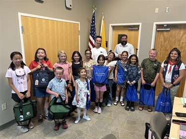 A group of kids stand with their bagged awards in a conference room.
