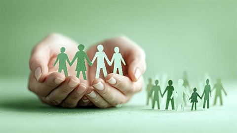 Photo of hands cupping paper cut-outs of people.