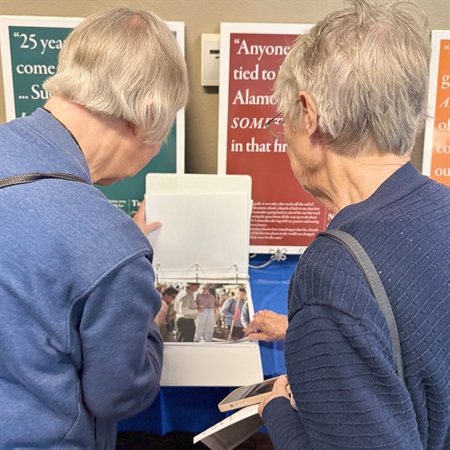Two community members read documents displayed at the Reflections on the Cerro Grande Fire: 25 Years Later event