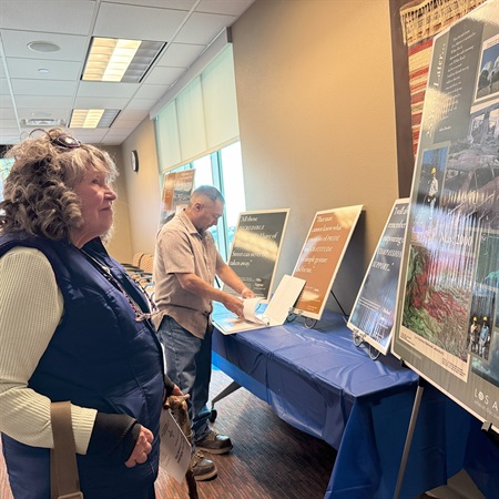 A community member regards posters of photos and quotes displayed at the Reflections on the Cerro Grande Fire: 25 Years Later event