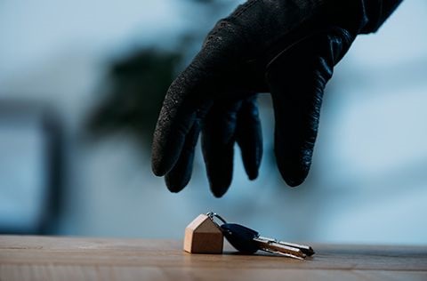 Photo of a gloved hand taking house keys off of a table